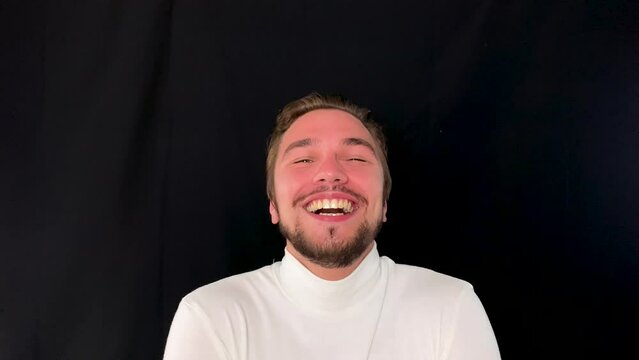 Young man with facial hair laughing uncontrollably, expressing joy and happiness
