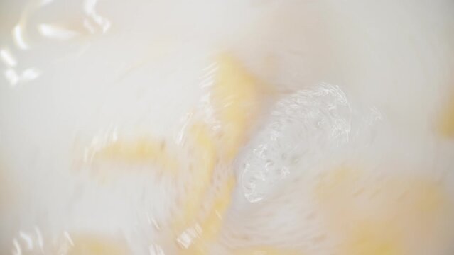 Wheat flakes rotate in milk, breakfast. olly slider close up inside. Slow motion