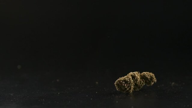 Marijuana buds falling down on a dark background.