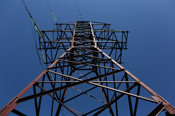 Metal electric tower of high voltage on background of blue color. Down view.