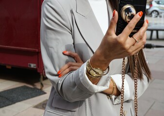 Oberkörper von junger Frau im Business Look mit schwarzem Handy in der Hand 