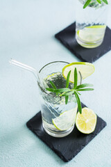 Detox drink water with lime and rosemary in glasses with eco straw on the table.  Vertical view. Close-up