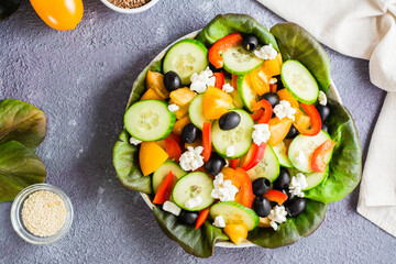 Greek salad of fresh vegetables, leaves and feta cheese on a plate on the table. Top view. Close-up