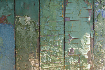 Old weathered boards, with peeling green and blue paint faded in the sun, cracks and colored spots. Textured background