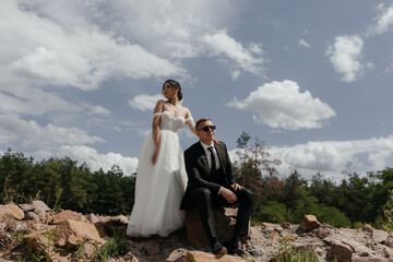 Naklejka premium Romantic wedding couple posing on top of mountains at sunset with amazing view. Beautiful newlyweds on their wedding day