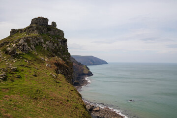 Fototapeta na wymiar Large mountains, cliffs on the ocean shore. Smoky ocean in cloudy weather. Lynmouth, Devon, England, UK