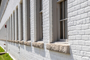 Exterior view down a long row of arched windows with precast concrete sills in a white brick two...