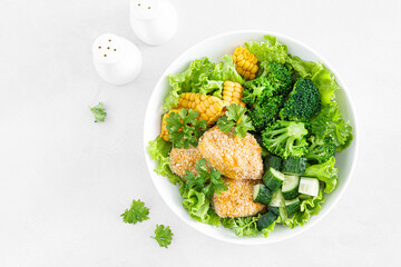 Chicken nuggets with broccoli, corn, cucumbers and salad lettuce. Top view