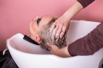 Shampoo washing of female head with long blonde hair in hairdressing salon