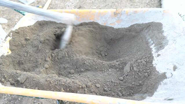 Removiendo arena y cemento en una carretilla para fraguar cemento para una reparaci&oacute;n
