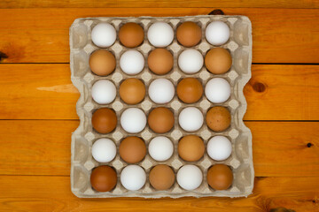 Chicken eggs in a package on the table. Brown and white chicken eggs in the egg tray in a checkerboard pattern. Natural eco-friendly products. Fresh chicken raw eggs in the chequerwise. Close-up