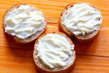 Sandwiches with cream cheese on the table. Sliced bread slices with soft cheese spread. Paste spread on a fresh French baguette. Homemade dessert for tea and coffee. Morning breakfast. Delicious snack