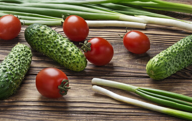 Fresh organic vegetables on a wooden table tomatoes, onions, cucumbers.