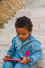 Black boy playing online on cell phone, surfing the internet. New generation addicted to the concept of gadgets. African American boy