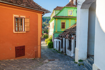 Stone paved medieval streets with colorful houses in Sighisoara, Transylvania region, Romania.
