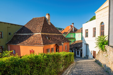 Fototapeta na wymiar Stone paved medieval streets with colorful houses in Sighisoara, Transylvania region, Romania.