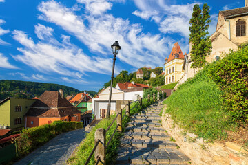 Stone paved alley on hillside to medieval fortified city of Sighisoara, Transylvania region, Romania