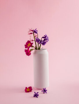 Various spring flowers in a white can against pink background. Minimal concept. Retro aesthetics of still life. Copy space.