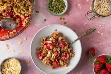 Berry crumble pie with strawberry, oat flakes, almonds and pumpkin seeds on pink background. Top view