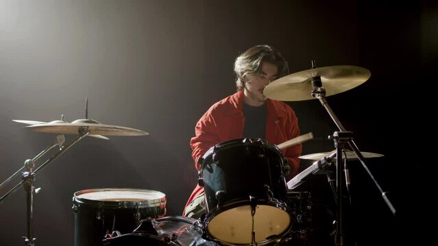 Young male drummer playing drums at music studio while rehearsing alone. Musician performing on percussion instruments. Music, leisure concept