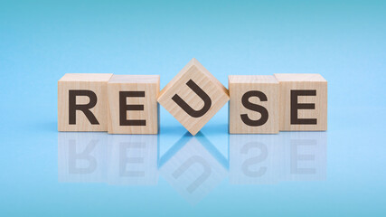 REUSE - word is written on wooden cubes on a bright blue background. close-up of wooden elements