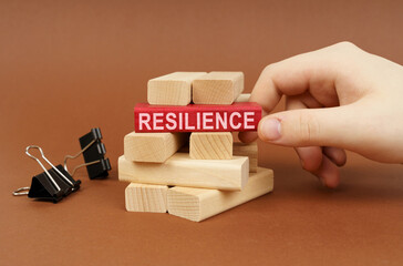 Clamps and wooden blocks lie on a brown surface, a person takes out a red block with the...