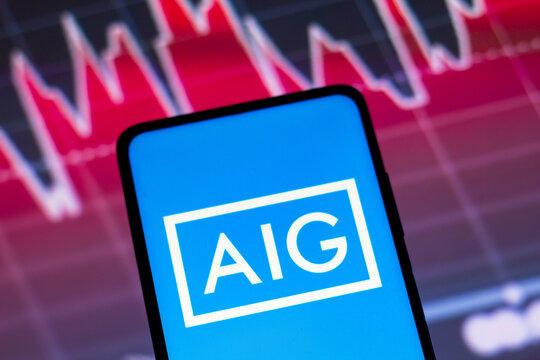 May 4, 2022, Brazil. In this photo illustration the American International Group (AIG) logo seen displayed on a smartphone screen, with graphic representation of the stock market in the background.