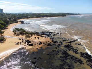 Beautiful beach with dark sands and black rocks like a volcano. Manguinhos, Espirito Santo, Brazil - aerial drone view