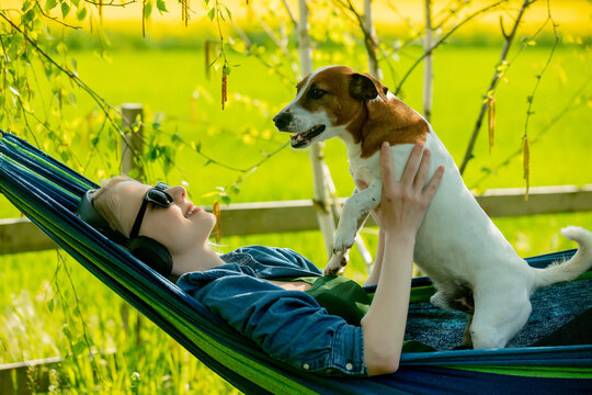 Woman With A Dog In Hammock In Countryside