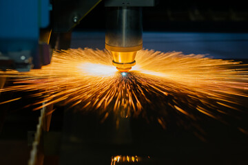 Automatic cnc laser cutting machine working with sheet metal with many orange sparks at factory,...