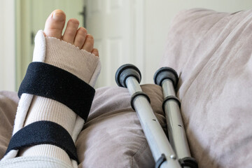 Close-up of a woman's foot which is injured and is wearing a brace and crutches