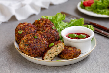 Homemade Meat cutlets (meatballs) served on a plate with green salad and tomato dipping sauce. Selective focus, gray concrete background. Horizontal - obrazy, fototapety, plakaty