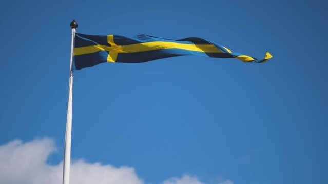 Swedish flags waving with the wind flow under the blue sky for national day celebration and symbol of european union. Swedish National day, midsummer. Slowmotion video with copyspace.