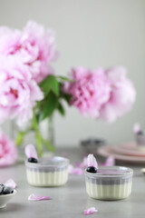 Homemade Italian dessert panna cotta with blue berries and bouquet of peony flowers on gray background. 