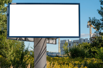 Advertising billboard mock-up near the construction site of modern apartment buildings