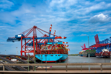 Cargo seaport in its working rhythm with many ships and cargo and cranes against the blue sky