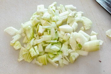 Composition with fresh onions on white table. chopped onions on cutting board, top view. Sliced onions on a cutting board to prepare meals