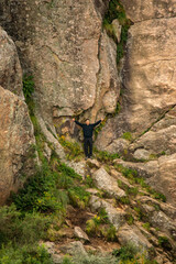 man at the base of a mountain with a huge rock behind him