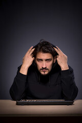 Young male hacker on grey background