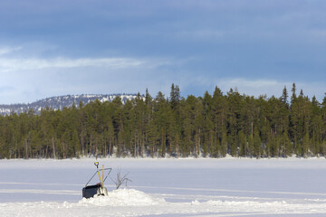 ice fishing on a frozen lake in finnish lapland