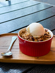 Apple peach crisp crumble with white ice cream on the wooden tray. Red small plate. Cream. Ice. Vanilla. Crisp. Oatmeal. Cooked. Dish. Snack. Cinnamon. Crust. Oat. Pie. Cake. Pastry