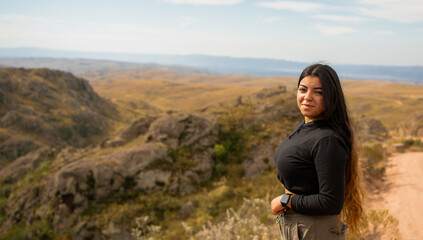 Naklejka premium Portrait of Latin woman dressed in black with a cap having fun during the day of trekking in the mountain forest - looking at the camera
