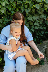 Joyful older sister holding younger sister, playing and laughing, having fun. Teen girl holding baby girl on summer day. Children with large age gap. Big age difference between siblings