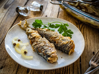 Fish dish - marinated fried herrings on wooden table
