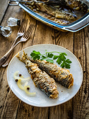 Fish dish - marinated fried herrings on wooden table
