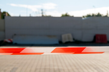 Red and white security tape with blurred background of of the construction site. Selective focus.