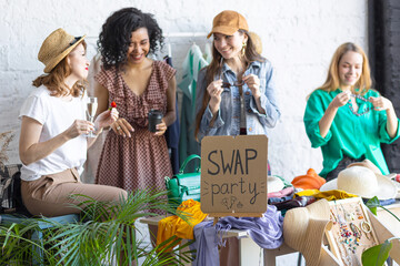 Young women at swap home party - clothes, shoes, bags, jewellery exchange between friends. Zero...