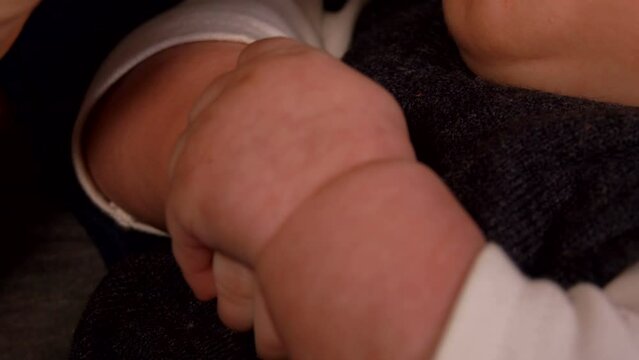 Super close-up of a cute little hand of the baby bottle feeding in mothers arms