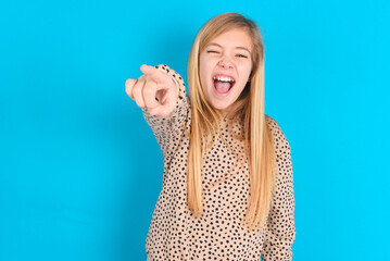 little caucasian kid girl wearing animal print sweater over blue background pointing displeased and...