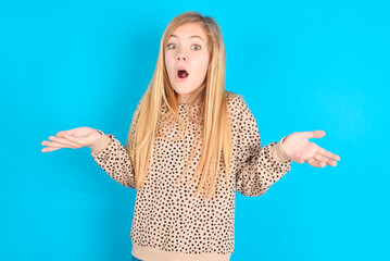 Frustrated little caucasian kid girl wearing animal print sweater over blue background feels...